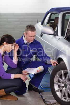 Mechanic touching the car wheel while looking at it