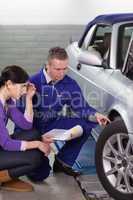 Mechanic touching the car wheel while looking at it