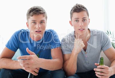 Two guys watching something as they look shocked