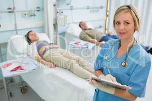 Nurse next to transfused patients writing on a clipboard