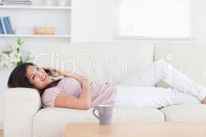 Woman resting in a sofa while holding a phone