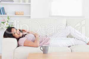 Woman resting in a sofa while holding a phone