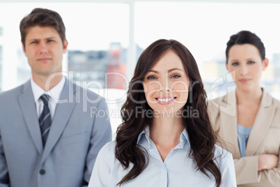 Young smiling woman standing in front of two co-workers