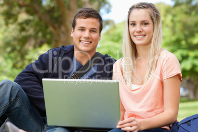 Portrait of two students laughing while sitting with a laptop