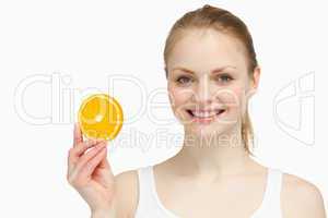 Cheerful woman presenting an orange slice