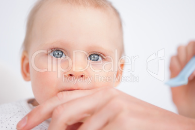 Beautiful baby biting the fingers of her mother