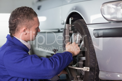 Concentrated mechanic repairing a car wheel