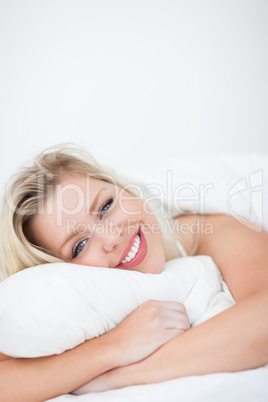 Young woman smiling while embracing a pillow