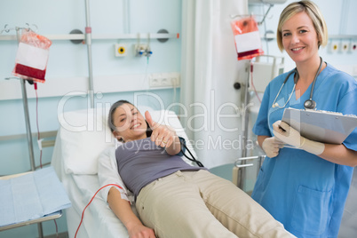 Nurse next to a patient while holding a clipboard