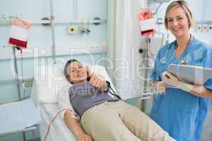 Nurse next to a patient while holding a clipboard