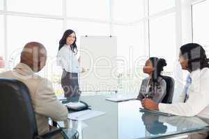 Businesswoman giving a presentation while her co-workers are lis