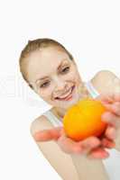 Cheerful woman holding a tangerine while looking at it