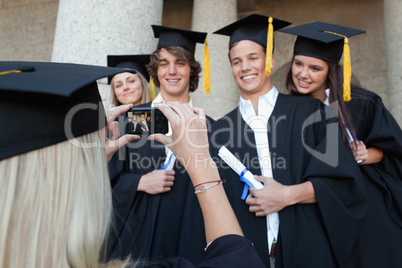 Close-up of a female graduate taking a picture of her friend