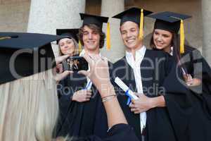 Close-up of a female graduate taking a picture of her friend