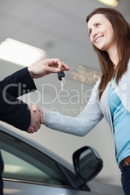 Woman receiving car keys while shaking hand