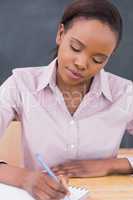 Black teacher writing on a notebook