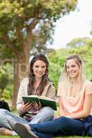 Cute teenagers sitting while studying with a textbook