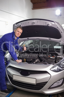 Mechanic leaning on a car with his thumb up