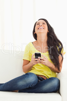 Happy Latino looking up while holding her smartphone