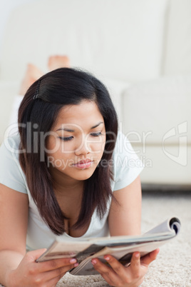 Woman reading a book while she is lying on the floor