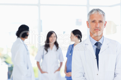 Mature doctor standing in the foreground and accompanied by his