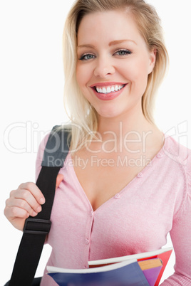 Young woman beaming while holding notebooks