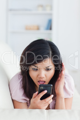 Chocked woman phoning while resting on a sofa