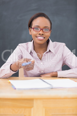 Teacher at desk holding a pen