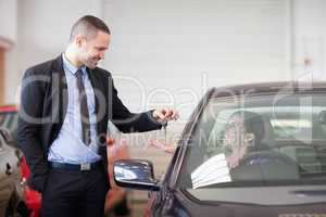Salesman smiling while giving keys to a woman
