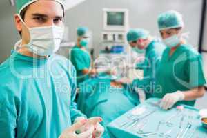 Surgeon wearing bloody gloves while looking at camera