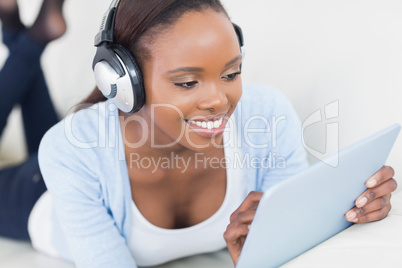 Black woman lying on front using a table computer