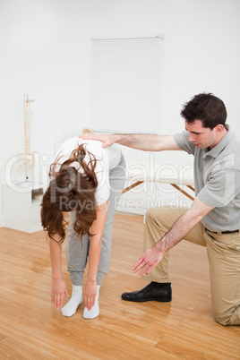 Doctor looking at a patient who is doing stretching exercises