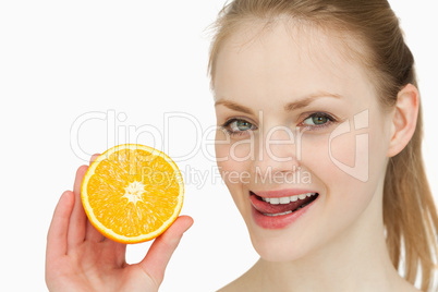 Woman holding an orange while placing her tongue on her lips