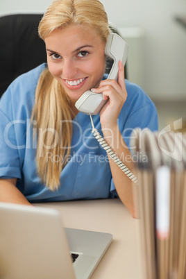 Blonde nurse calling while looking at camera