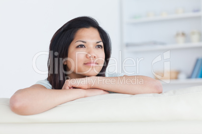 Thinking woman crossing her arms as she stands on a white couch
