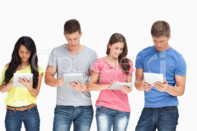 A group standing beside each other and using their tablet pc's