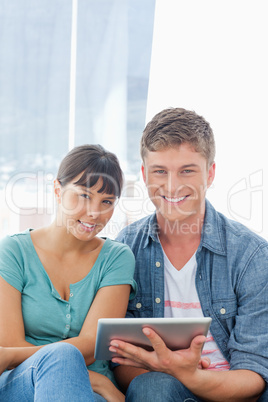 Close up of a smiling couple with a tablet pc looking into the c
