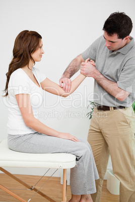 Serious physiotherapist touching the elbow of a woman