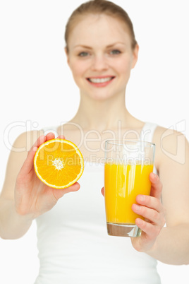 Smiling woman presenting an orange while holding a glass