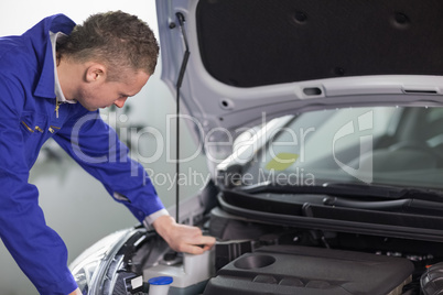 Mechanic looking at an engine while leaning on it