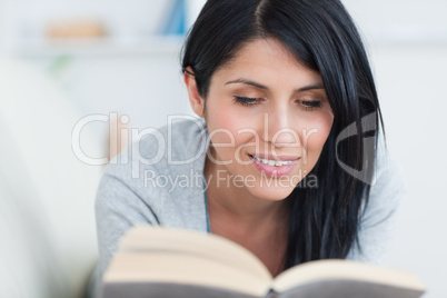 Woman smiles as she holds a book on a couch