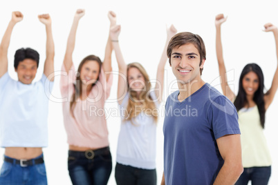 Smiling man with people behind him raising their arms