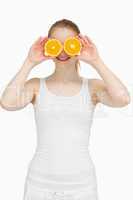 Joyful woman placing oranges on her eyes