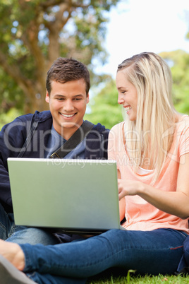 Close-up of young people laughing while sitting with a laptop