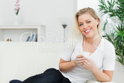 Woman seating on a sofa with a cup