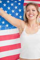 Cheerful blonde woman raising the Stars and Stripes flag