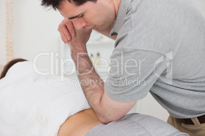 Woman lying forward while a physiotherapist is massaging her bac