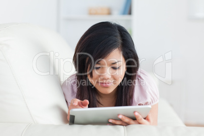 Woman lying on a couch while holding a tablet