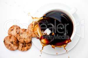 Sugar dropping in a cup of coffee with cookies