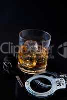 Whiskey on the rocks with car key and handcuff